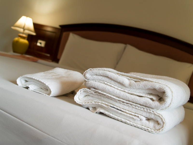 Drei Frotteehandtücher auf einem frisch bezogenen Hotelbett